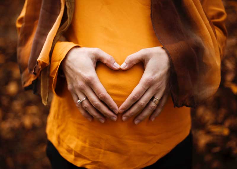 Maternity Shoot Captions: Heart made with hands over a baby bump.